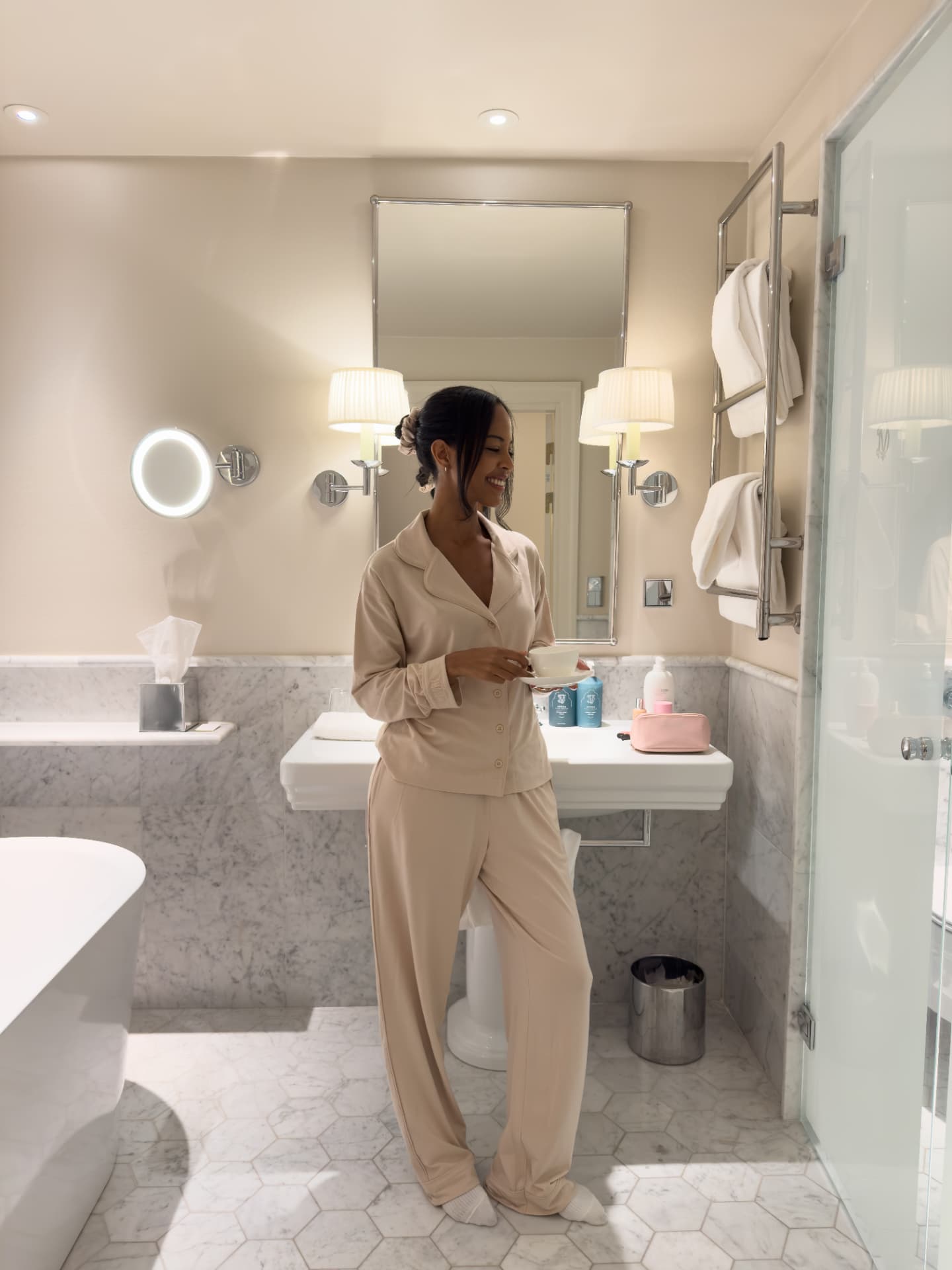 Creator in a champagne Melowe set enjoying coffee in a marble hotel bathroom